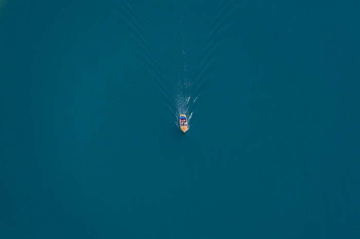 Boat on a blue lake creating ripples