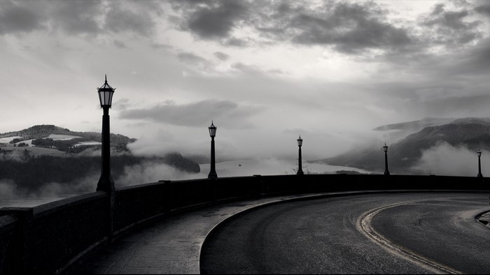 Monochrome landscape with lamps and a winding road