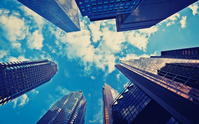 Looking up at skyscrapers against a blue sky with clouds