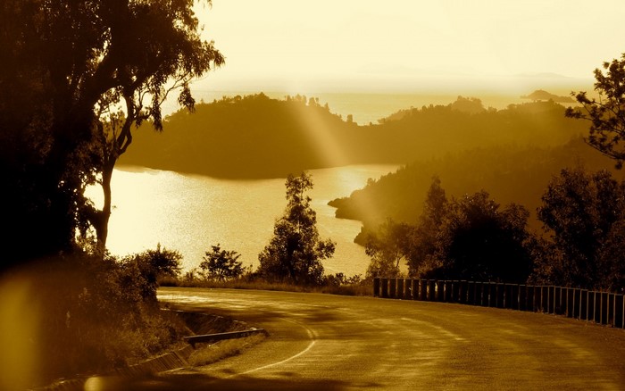 Road overlooking a lake with sun rays