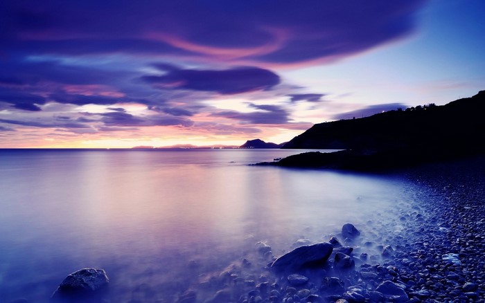 Purple sunset over a rocky coastline and calm sea