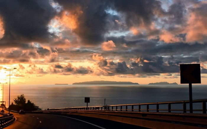 Sunset over the sea with islands and a highway