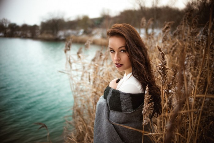 Woman wrapped in blanket by lake