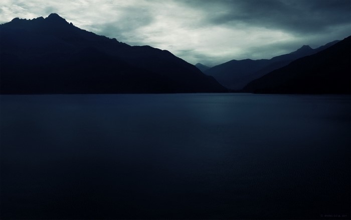 Dark mountains over a still lake at dawn