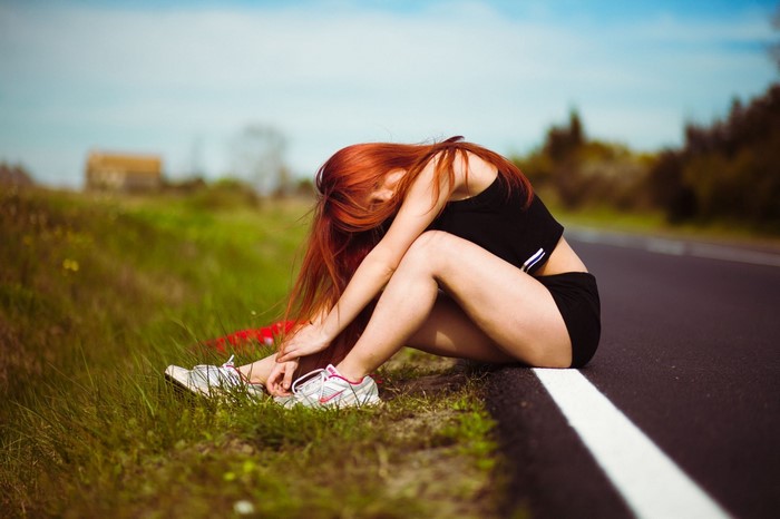 Redhead woman sitting on the side of the road