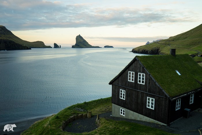 House with grass roof on a hill overlooking a bay with islands