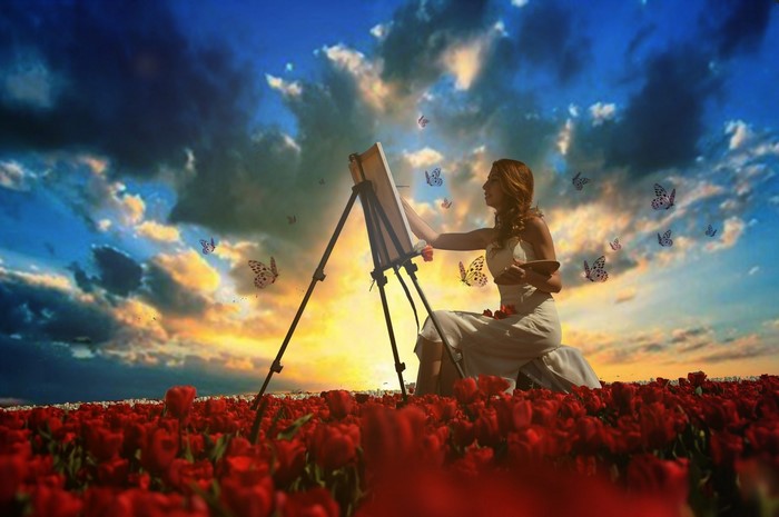 Woman painting in a field of tulips at sunset with butterflies