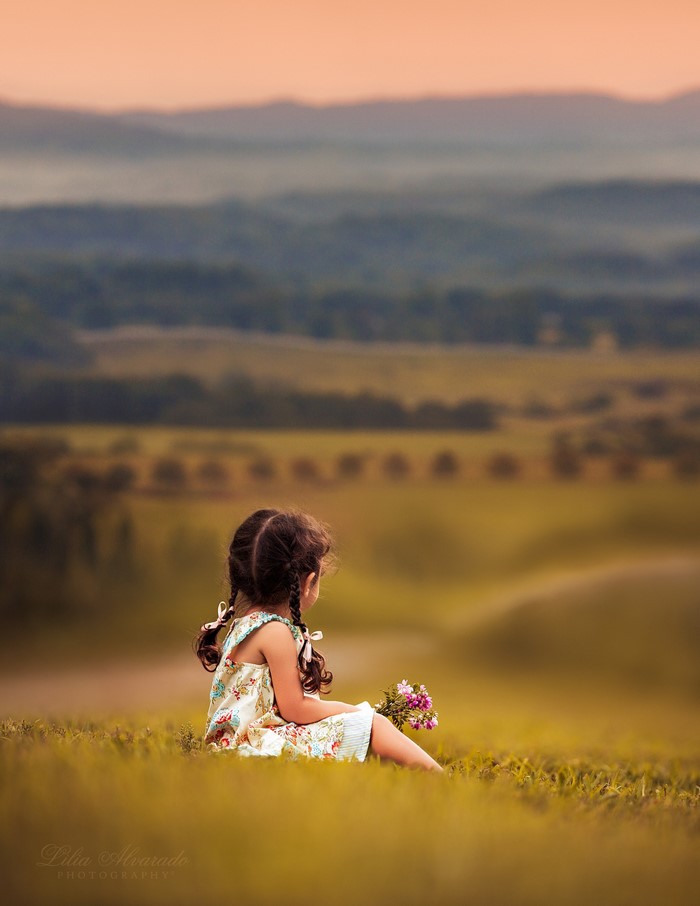 Girl with flowers in a grassy landscape at sunset