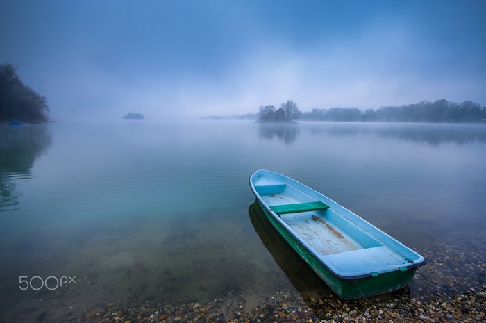 A lone boat on a misty lake at dawn