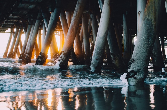 Sunlight reflecting on the water under a pier