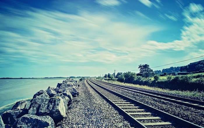 Railway tracks along the sea with a cloudy sky