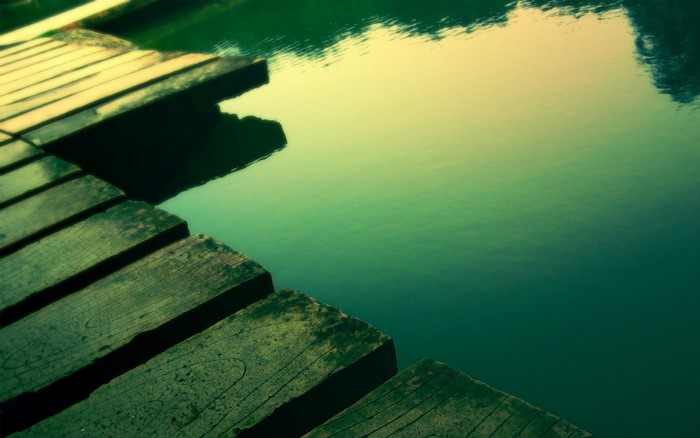Wooden pier over green water with reflections