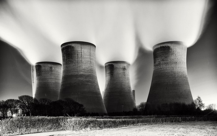 Monochrome photography of industrial cooling towers emitting steam