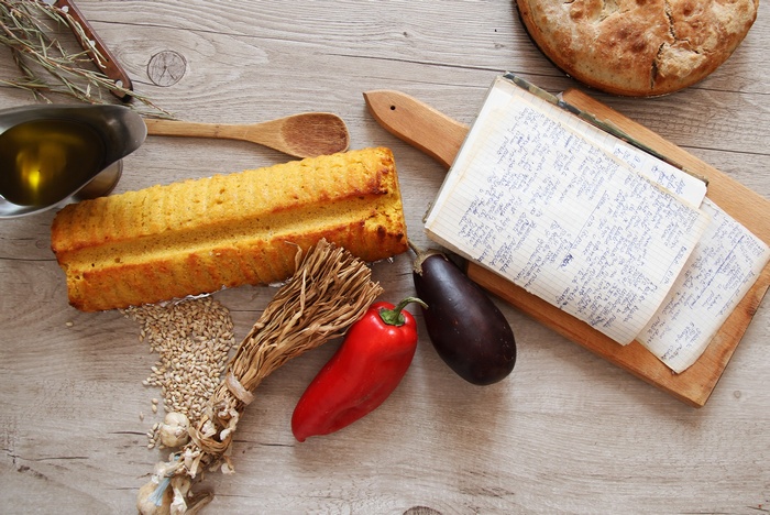 Bread, vegetables, and a recipe book on a wooden table