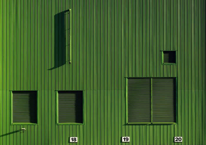 Green corrugated metal wall with windows and numbers