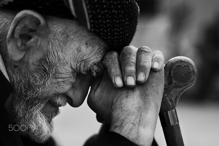 Close up of an elderly man resting his head on his hand
