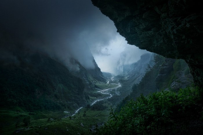 Misty valley with a winding river seen from a cave