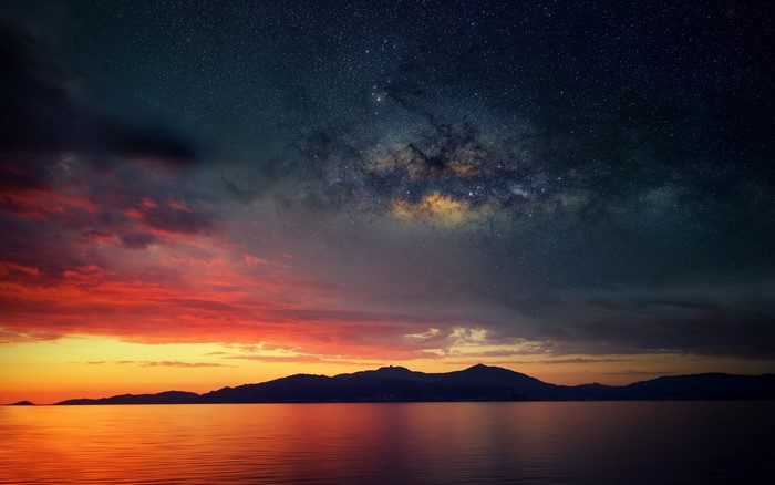 Milky Way over ocean and mountains at sunset