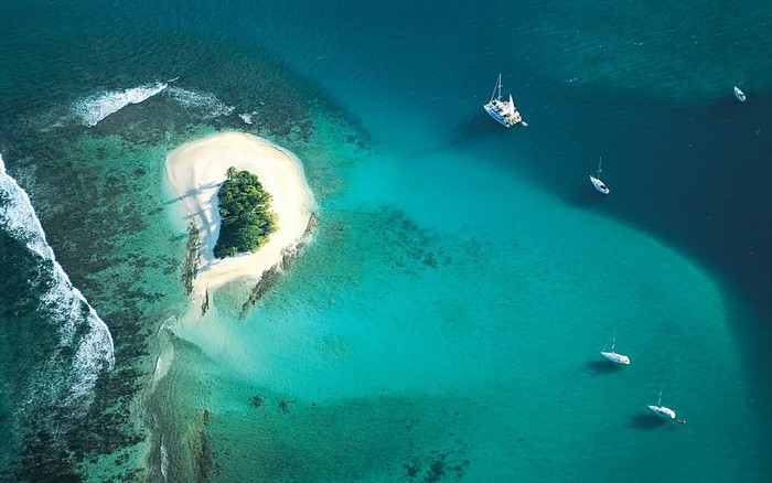 Aerial view of a tropical island with sailboats in turquoise water
