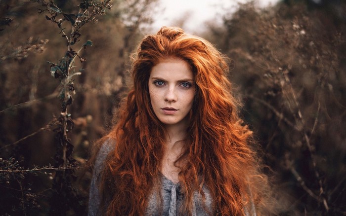 Woman with long red wavy hair and freckles