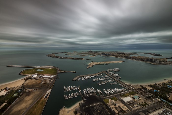 Aerial view of Palm Jumeirah, Dubai with yachts and cloudy sky