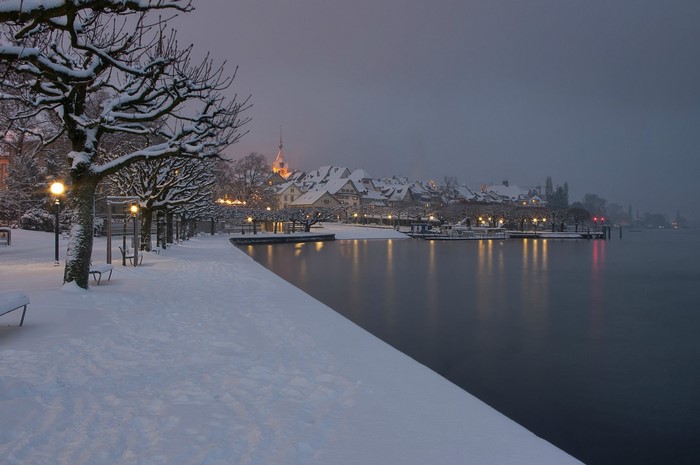 Snowy waterfront town at dusk with reflections