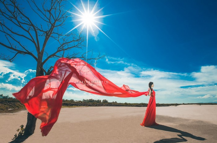 Woman in red dress with red fabric in sunlight