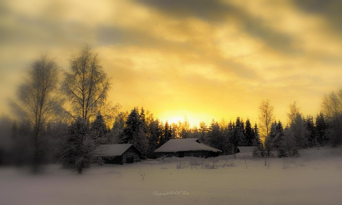 Winter sunset over a snowy landscape with cabins and trees