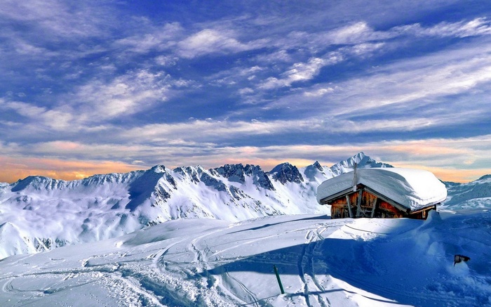 Snowy mountain range with a cabin and blue sky