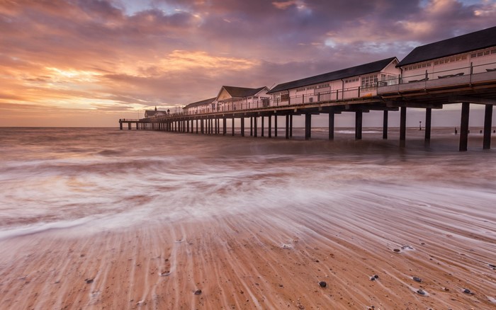 Sunset over a pier and beach with waves