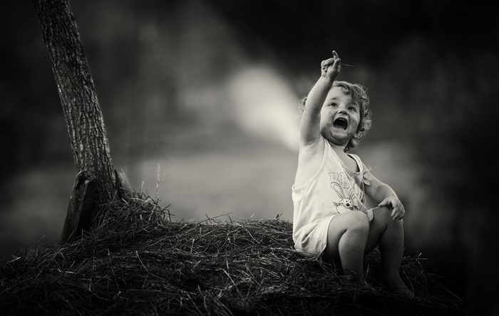 Child sitting on hay with stick