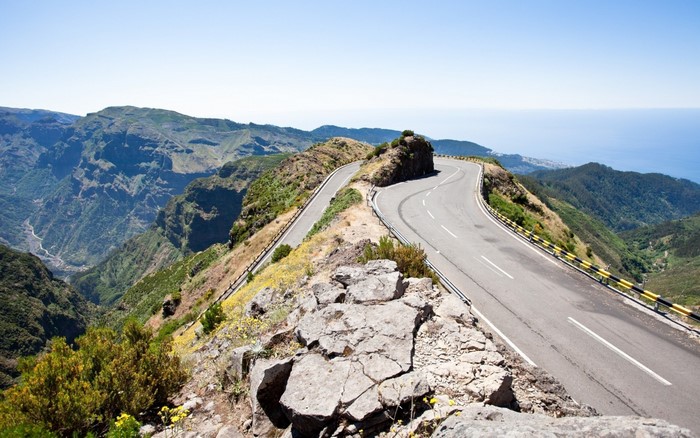 Mountain road winding through a scenic landscape with ocean view