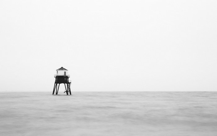 Black and white lighthouse on stilts in the sea