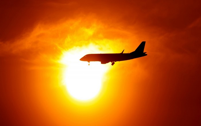 Airplane silhouetted against a bright sunset