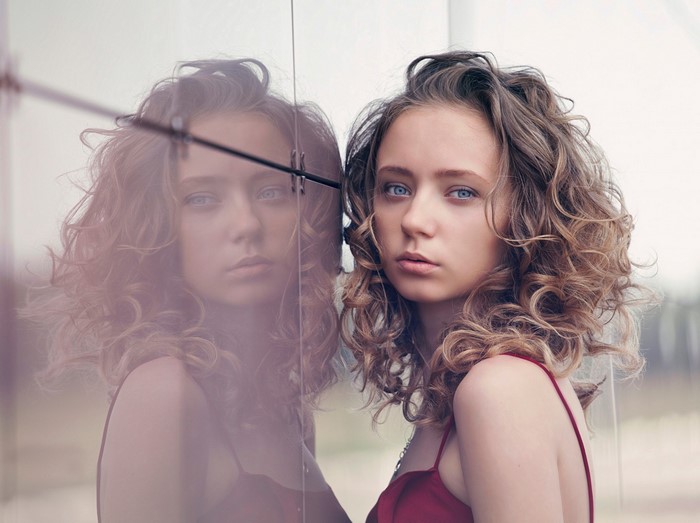 Woman with curly hair reflected in glass