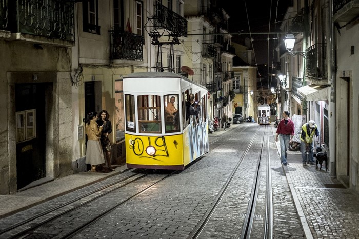 Yellow tram on a cobblestone street at night in Lisbon