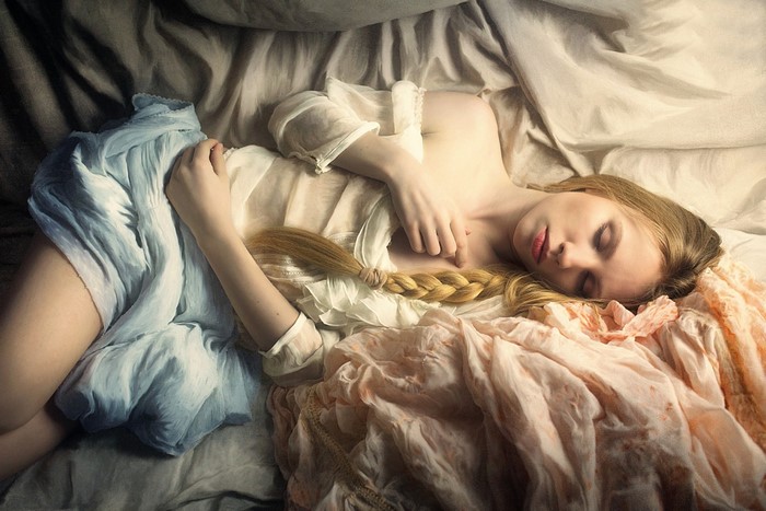 Woman sleeping with blonde braid and flowing fabrics