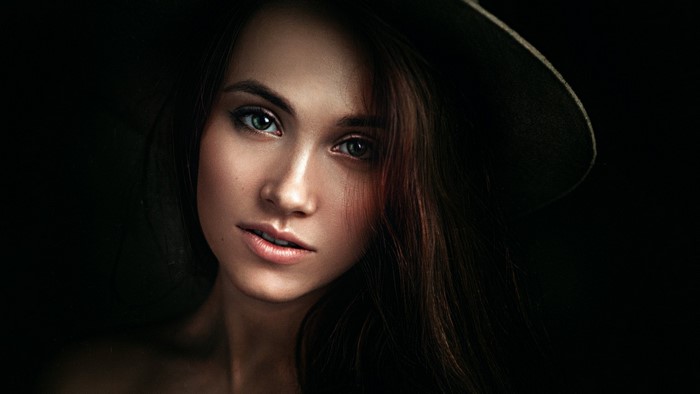 Woman with long brown hair and green eyes wearing a hat