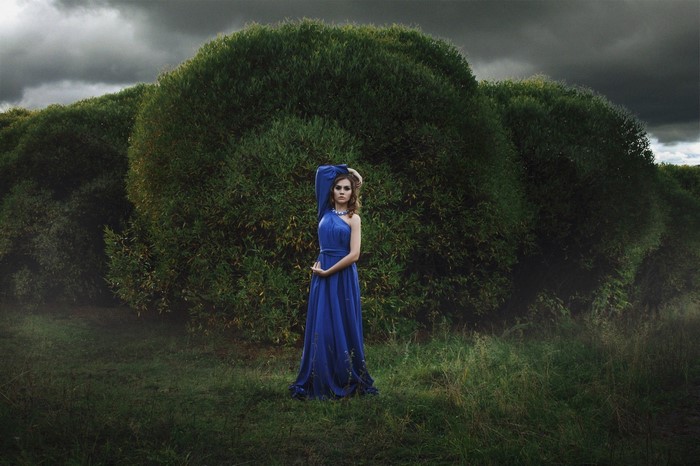 Woman in blue dress in front of trees