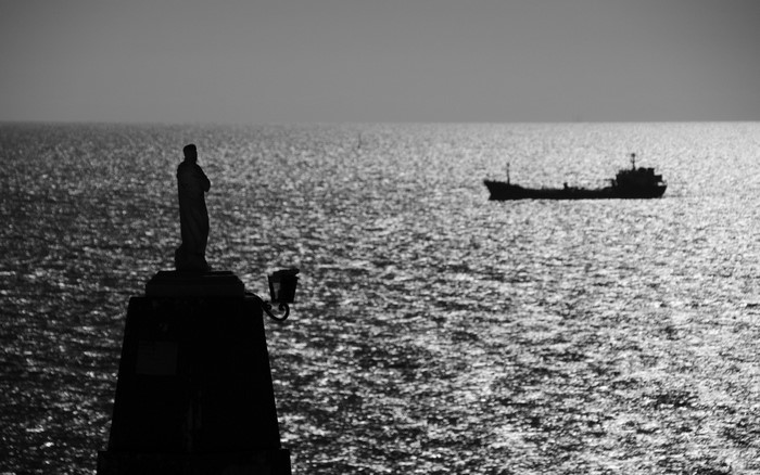 Silhouette of a statue and a ship on the sea