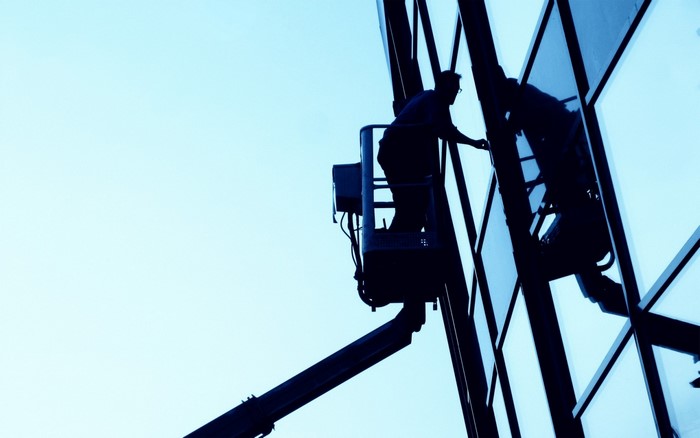 Silhouette of a window cleaner in a cherry picker