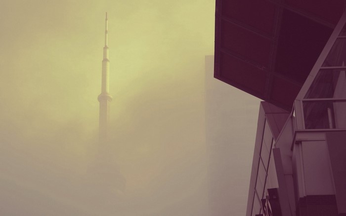 Tower in fog with modern building architecture