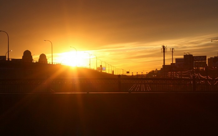 Sunset over a city bridge with streetlights and towers