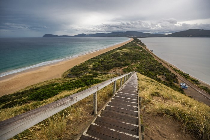 Wooden stairs leading to a beach and bay with mountains
