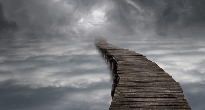 Wooden walkway through clouds towards light
