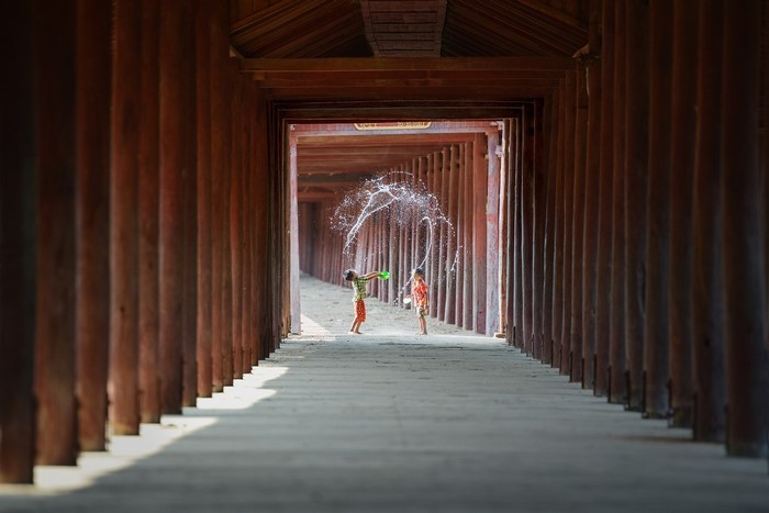Children playing with water in a wooden temple corridor
