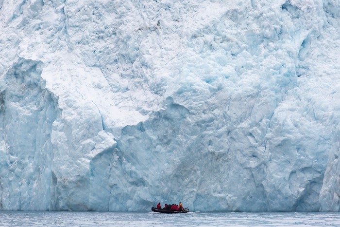 People in a boat near a massive glacier