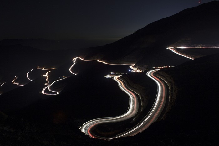 Nighttime mountain road with light trails