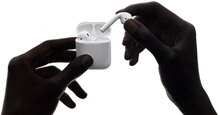 Hands holding Apple AirPods and charging case
