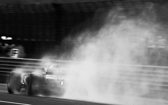 Formula 1 car kicking up dust on a race track